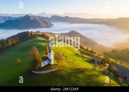 Die Kirche St. Thomas bei Sonnenaufgang im Herbst aus der Vogelperspektive. Sveti Tomaz, Skofja Loka, Oberkarniola, Slowenien, Europa. Stockfoto