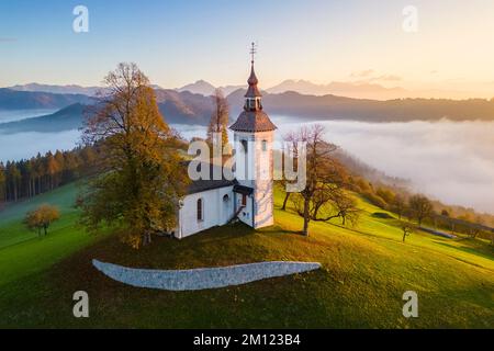 Die Kirche St. Thomas bei Sonnenaufgang im Herbst aus der Vogelperspektive. Sveti Tomaz, Skofja Loka, Oberkarniola, Slowenien, Europa. Stockfoto