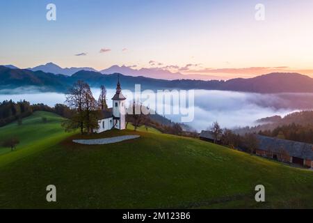 Die Kirche St. Thomas bei Sonnenaufgang im Herbst aus der Vogelperspektive. Sveti Tomaz, Skofja Loka, Oberkarniola, Slowenien, Europa. Stockfoto