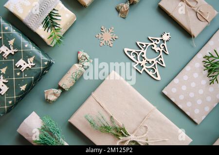 Umweltfreundliche Weihnachtsgestaltung mit Geschenkboxen aus wiederverwendbarem Papier und natürlicher Einrichtung auf blaugrünem Hintergrund, Draufsicht. Umgebung ohne Verschwendung Stockfoto