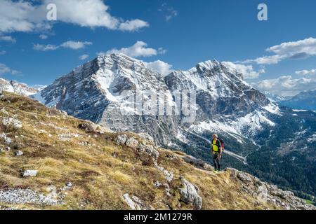 Wengen, hohe Abtei, Provinz Bozen, Südtirol, Italien. Ein Kletterer auf dem Aufstieg nach Paresberg. Im Hintergrund die Neunerspitze und die Zehnerspitze Stockfoto