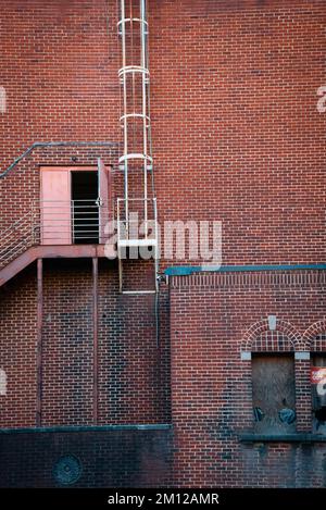 Altes Ziegelgebäude mit Stahltreppe und offener Tür in Charlotte, NC. Stockfoto