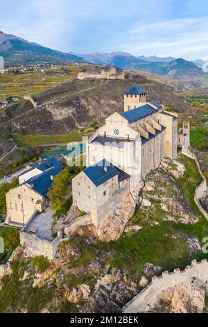 Blick aus der Vogelperspektive auf die Basilique de Valère, die die Stadt Sion und die umliegenden Weinberge im Herbst dominiert. Kanton Wallis, Tal des Rhône, Schweiz. Stockfoto