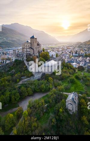 Blick aus der Vogelperspektive auf die Basilique de Valère, die die Stadt Sion und die umliegenden Weinberge im Herbst dominiert. Kanton Wallis, Tal des Rhône, Schweiz. Stockfoto