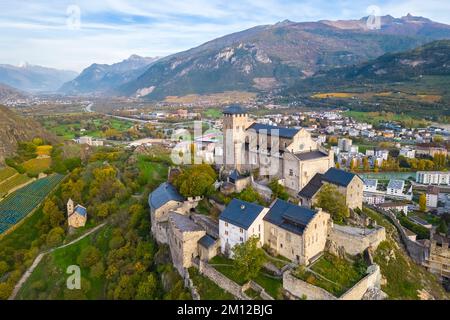 Blick aus der Vogelperspektive auf die Basilique de Valère, die die Stadt Sion und die umliegenden Weinberge im Herbst dominiert. Kanton Wallis, Tal des Rhône, Schweiz. Stockfoto