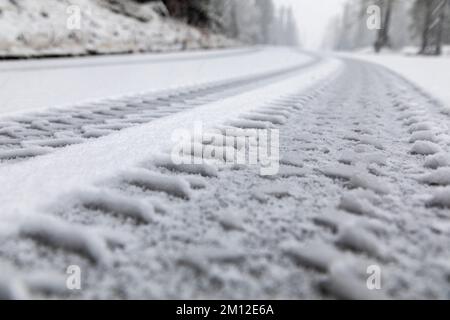 Italien, Venetien, Belluno, Dolomiten. Spuren eines schweren Fahrzeugs im frischen Schnee entlang einer Bergstraße Stockfoto