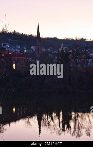 Bingen am Rhein - 10. Januar 2021: Kirche und andere Gebäude mit Wasserreflexion an einem Winterabend in Deutschland. Stockfoto