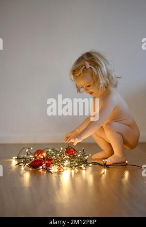 Mädchen, 14 Monate, spielt mit Weihnachtsdekorationen, Weihnachtsbällen, Feenlichtern, Stuttgart, Baden-Württemberg, Deutschland, Europa Stockfoto