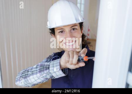 Glückliche weibliche Arbeiterin, die das Fenster schraubt Stockfoto