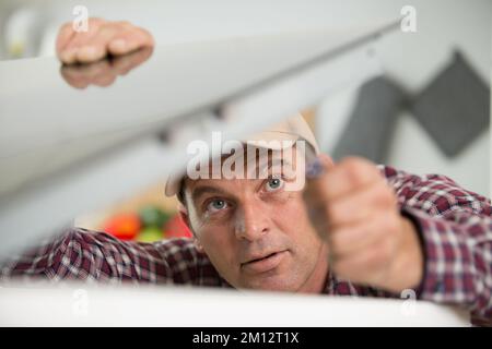 Nahaufnahme eines Technikers, der an einem defekten Gerät arbeitet Stockfoto