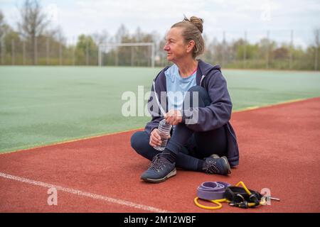 Seniorin auf dem Sportplatz während des Sommers. Stockfoto