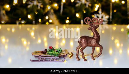 Der Raindeer steht mit einem Schlitten auf einem Weihnachtshintergrund. Stockfoto