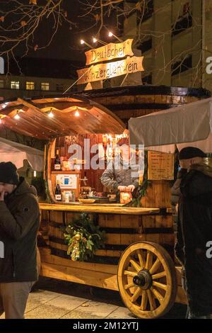 Dresdner Weihnachtsmärkte im Winter 2022, beleuchtet in der Nacht. Im Vordergrund, eine der kleinen Hütten und ein Verkäufer Stockfoto