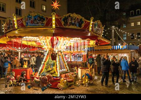 Dresdner Weihnachtsmärkte im Winter 2022, beleuchtet in der Nacht. Im Vordergrund ein Karussell Stockfoto