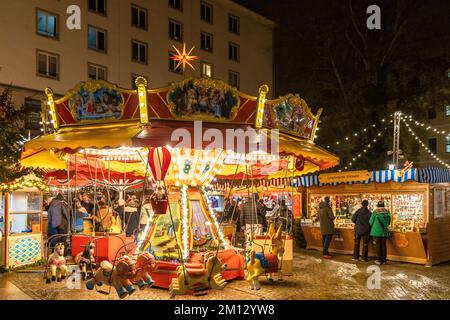 Dresdner Weihnachtsmärkte im Winter 2022, beleuchtet in der Nacht. Im Vordergrund ein Karussell Stockfoto