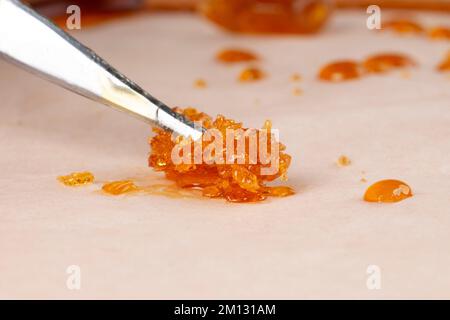 goldener Pho-Cannabisbröckel, Harz mit frischem, hohem thc-Terpen auf beigefarbenem Hintergrund. Stockfoto