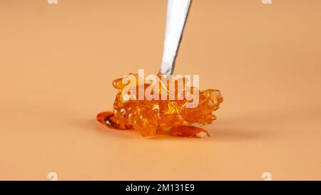 goldener Pho-Cannabisbröckel, Harz mit frischem, hohem thc-Terpen auf beigefarbenem Hintergrund. Stockfoto