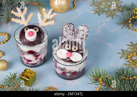 Kuchen in Gläsern in Form von süßen Kaninchen und Hirschen mit Kirschen, Schokoladenkeks und Kokosflocken Stockfoto