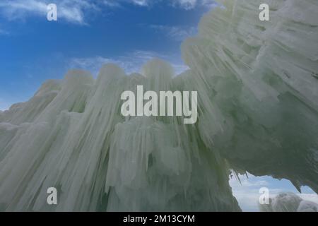 Eine imposante Mauer aus Eis und Eiszapfen kontrastierte mit einem leuchtend blauen Himmel mit Zirruswolken bei der Eisschlössershow in Lake Geneva, Wisconsin, Stockfoto
