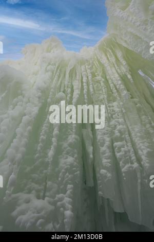 Eine imposante Mauer aus Eis und Eiszapfen kontrastierte bei der Ice Castles Show im Lake Geneva, Wisconsin, USA, mit einem blauen Himmel und Zirruswolken Stockfoto