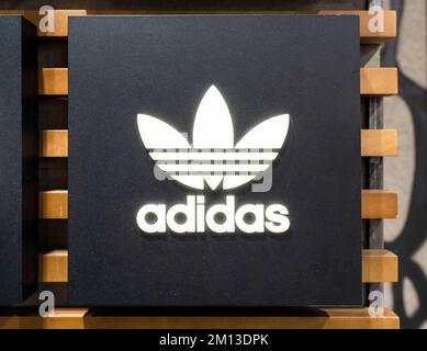 Adidas Logo an der Wand eines Sportschuhgeschäfts. Stockfoto