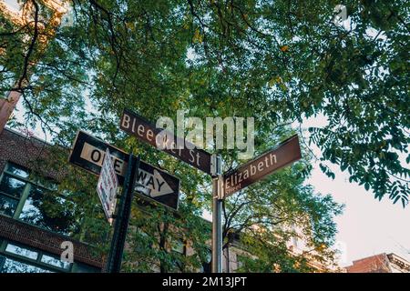 New York, USA - 2021. November 2022: Niedrige Sicht auf ein Straßenschild an der Ecke Bleecker Street und Elizabeth Street, einige der bekanntesten Stockfoto