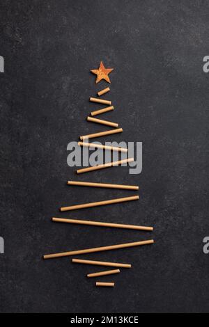 Kreativer Weihnachtsbaum aus Papierhalmen für Cocktails auf dunklem Hintergrund Stockfoto