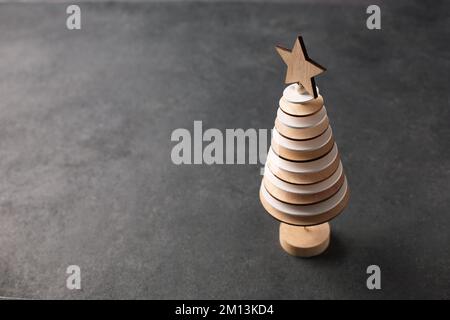 Kreativer Weihnachtsbaum aus Holzkreisen auf dunklem Hintergrund Stockfoto