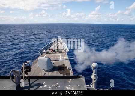 221206-N-YV347-2243 PAZIFIK (6. Dez. 2022) der Guided-Raketenkreuzer USS Bunker Hill (CG 52) der Ticonderoga-Klasse feuert während einer Trainingsübung seine 45 5-Zoll-MK-Pistole ab. Bunker Hill, Teil der Nimitz Carrier Strike Group, führt derzeit Routinevorgänge durch. (USA Marinebild von Mass Communication Specialist 3. Class Jordan Jennings) Stockfoto