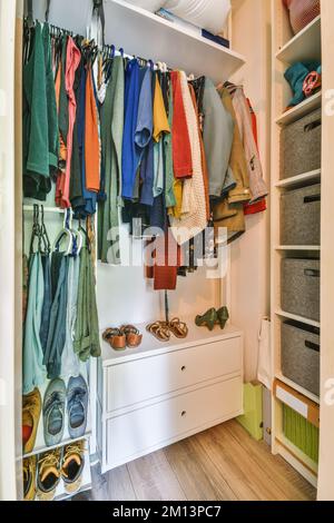 Die Innenseite eines Schranks mit vielen Kleidungsstücken, die an Haken, Schuhen und anderen Gegenständen hängen, die zur Aufbewahrung verwendet werden Stockfoto