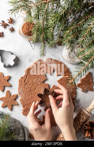 Frauenhände schneiden Formen und backen Kekse. Ich mache Weihnachtskekse. Draufsicht von oben, flach liegend Stockfoto