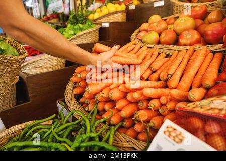 Kauf von frischen Bio-Produkten auf dem Bauernmarkt. Eine Frau wählt auf einem Lebensmittelmarkt frische Kräuter, Gemüse und Früchte. Stockfoto