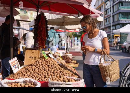 Frau wählt auf dem Markt Nüsse und getrocknete Früchte. Lächelnde junge Frau, die Bio-Nüsse wählt. Stockfoto