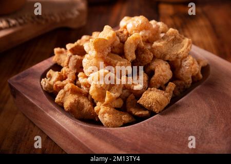 Chicharronen. Frittierte Schweineschinden, knusprige Schweinehaut, traditionelle mexikanische Zutaten oder Snack mit Zitronensaft und roter heißer Chilisauce. Stockfoto