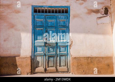 Rustikale alte Holztür mit strukturierter wandfassade aus lehmziegeln in Cusco, Peru Stockfoto