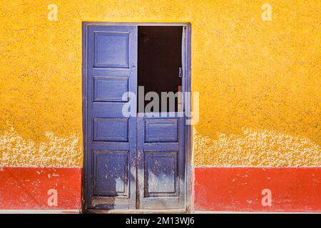 Rustikale alte Holztür mit strukturierter wandfassade aus lehmziegeln in Cusco, Peru Stockfoto