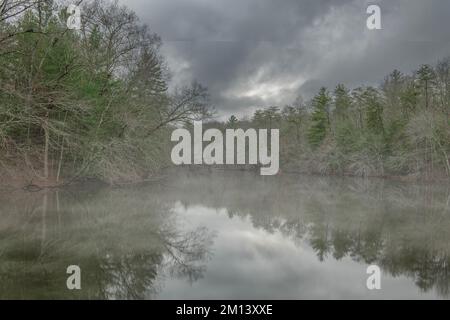 Das glasige Wasser am Byrd Creek Lake im Cumberland State Park, Tennessee, bietet an einem kalten, regnerischen Tag eine wunderschöne Kulisse für Naturszenen. Stockfoto