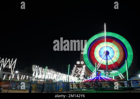 Lange Belichtung, langsame Verschlusszeit Aufnahme eines sich drehenden Riesenrads mit wunderschönen Lichtern auf der indian Fun Fair bei Nacht Stockfoto