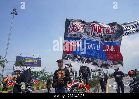 Malang, Ost-Java, Indonesien. 8.. Dezember 2022. Ein Demonstrante trägt während des Protests eine Protestflagge. Aremania, die Anhänger des FC Arema, hielt eine Kundgebung ab und blockierte an einigen Stellen in Malang die Straßen, um gegen den legalen Prozess der Tragödie der Fußball-Stampede zu protestieren, bei der am 1. Oktober 2022 135 Menschen durch das Tränengas der Polizei im Kanjuruhan-Stadion ums Leben kamen. (Kreditbild: © Dicky Bisinglasi/SOPA Bilder über ZUMA Press Wire) Stockfoto