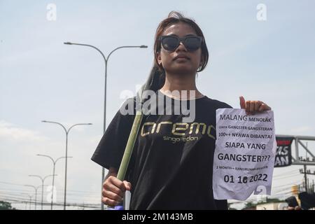 Malang, Ost-Java, Indonesien. 8.. Dezember 2022. Ein Demonstrante hält während des Protests eine schwarze Flagge und ein Plakat. Aremania, die Anhänger des FC Arema, hielt eine Kundgebung ab und blockierte an einigen Stellen in Malang die Straßen, um gegen den legalen Prozess der Tragödie der Fußball-Stampede zu protestieren, bei der am 1. Oktober 2022 135 Menschen durch das Tränengas der Polizei im Kanjuruhan-Stadion ums Leben kamen. (Kreditbild: © Dicky Bisinglasi/SOPA Bilder über ZUMA Press Wire) Stockfoto