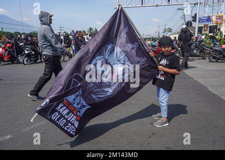 Malang, Ost-Java, Indonesien. 8.. Dezember 2022. Ein kleines Kind hält während des Protests eine Flagge. Aremania, die Anhänger des FC Arema, hielt eine Kundgebung ab und blockierte an einigen Stellen in Malang die Straßen, um gegen den legalen Prozess der Tragödie der Fußball-Stampede zu protestieren, bei der am 1. Oktober 2022 135 Menschen durch das Tränengas der Polizei im Kanjuruhan-Stadion ums Leben kamen. (Kreditbild: © Dicky Bisinglasi/SOPA Bilder über ZUMA Press Wire) Stockfoto