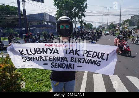 Malang, Ost-Java, Indonesien. 8.. Dezember 2022. Ein Demonstrant trägt ein Banner, auf dem er seine Meinung während des Protests zum Ausdruck bringt. Aremania, die Anhänger des FC Arema, hielt eine Kundgebung ab und blockierte an einigen Stellen in Malang die Straßen, um gegen den legalen Prozess der Tragödie der Fußball-Stampede zu protestieren, bei der am 1. Oktober 2022 135 Menschen durch das Tränengas der Polizei im Kanjuruhan-Stadion ums Leben kamen. (Kreditbild: © Dicky Bisinglasi/SOPA Bilder über ZUMA Press Wire) Stockfoto