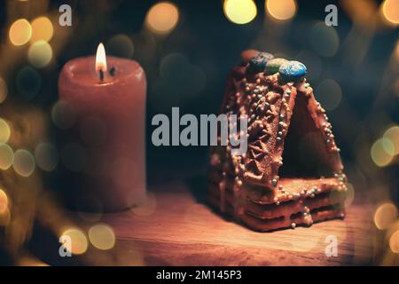 Weihnachtstisch. Kerzen, Orangen und Zimtstangen auf Holzhintergrund. Wunderschöner Bokeh-Effekt von einer Girlande. Stockfoto