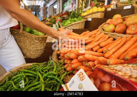 Kauf von frischen Bio-Produkten auf dem Bauernmarkt. Eine Frau wählt auf einem Lebensmittelmarkt frische Kräuter, Gemüse und Früchte. Stockfoto