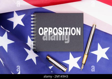 Amerikanisches Konzept. Die US-Flagge hat einen Stift und ein Notizbuch mit der Aufschrift - OPPOSITION Stockfoto