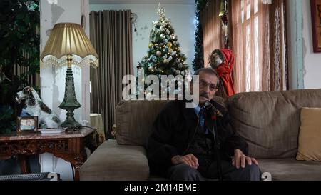 Ein älterer christlicher Palästinenser sieht deprimiert aus, wenn er zu Weihnachten in der palästinensischen Stadt Beit Sahour oder Bayt Sahur in seinem Haus sitzt. Westjordanland Israel Stockfoto