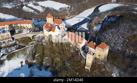 Eine Drohnenaufnahme von Schloss Veveri mit Waldbäumen in Brünn, Tschechien und verschneiten Straßen Stockfoto