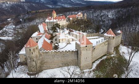 Eine Drohnenaufnahme von Schloss Veveri mit Waldbäumen auf verschneiten Straßen in Brünn, Tschechien im Winter Stockfoto