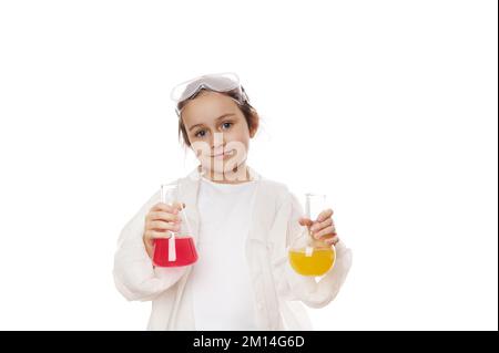 Niedliches kleines Mädchen im Laborkittel, Posen mit Laborkolben mit bunten chemischen Lösungen auf weißem Hintergrund Stockfoto