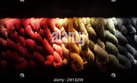 Ein Band aus farbiger und gewebter Wolle auf schwarzem Hintergrund. Stockfoto